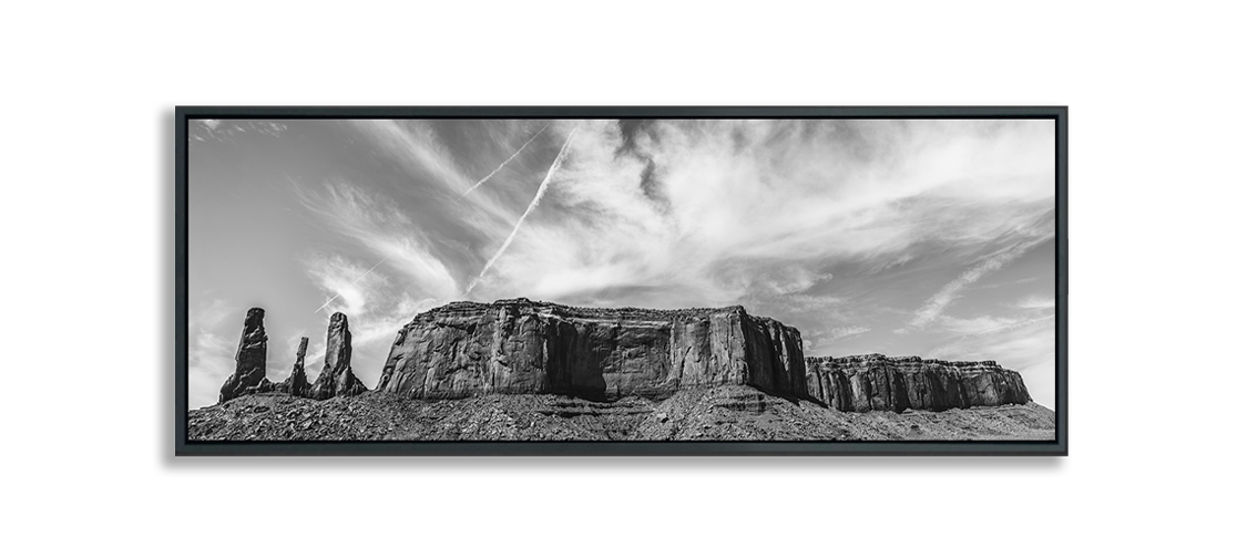 Monument Valley Three Sisters next to Desert Butte against dramatic clouds in sky