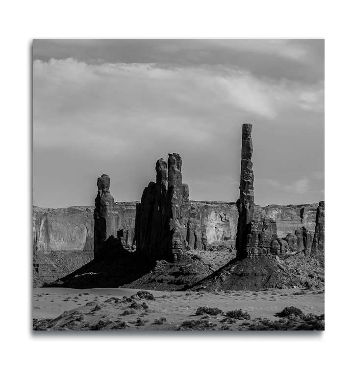 Monument Valley Square Print on Metal slender rock formations against desert rock ridge in background black and white