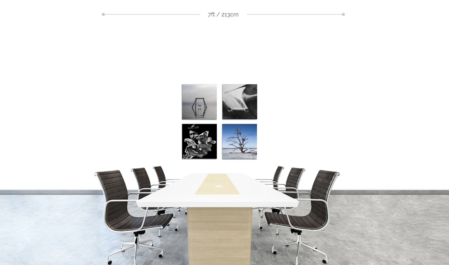 Set of four square metal prints arranged in square formation on wall behind boardroom table with chairs