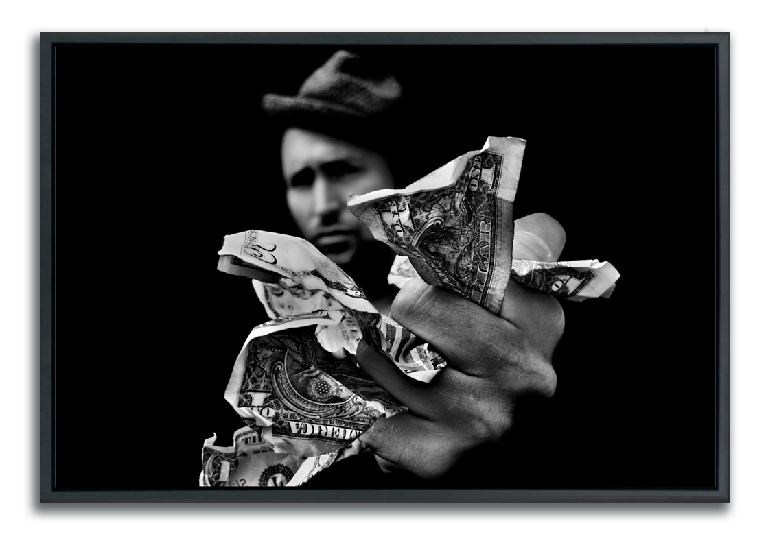 Black and white framed fine art photograph man wearing hat out of focus in background with hand outstretched holding fistful of money in foreground