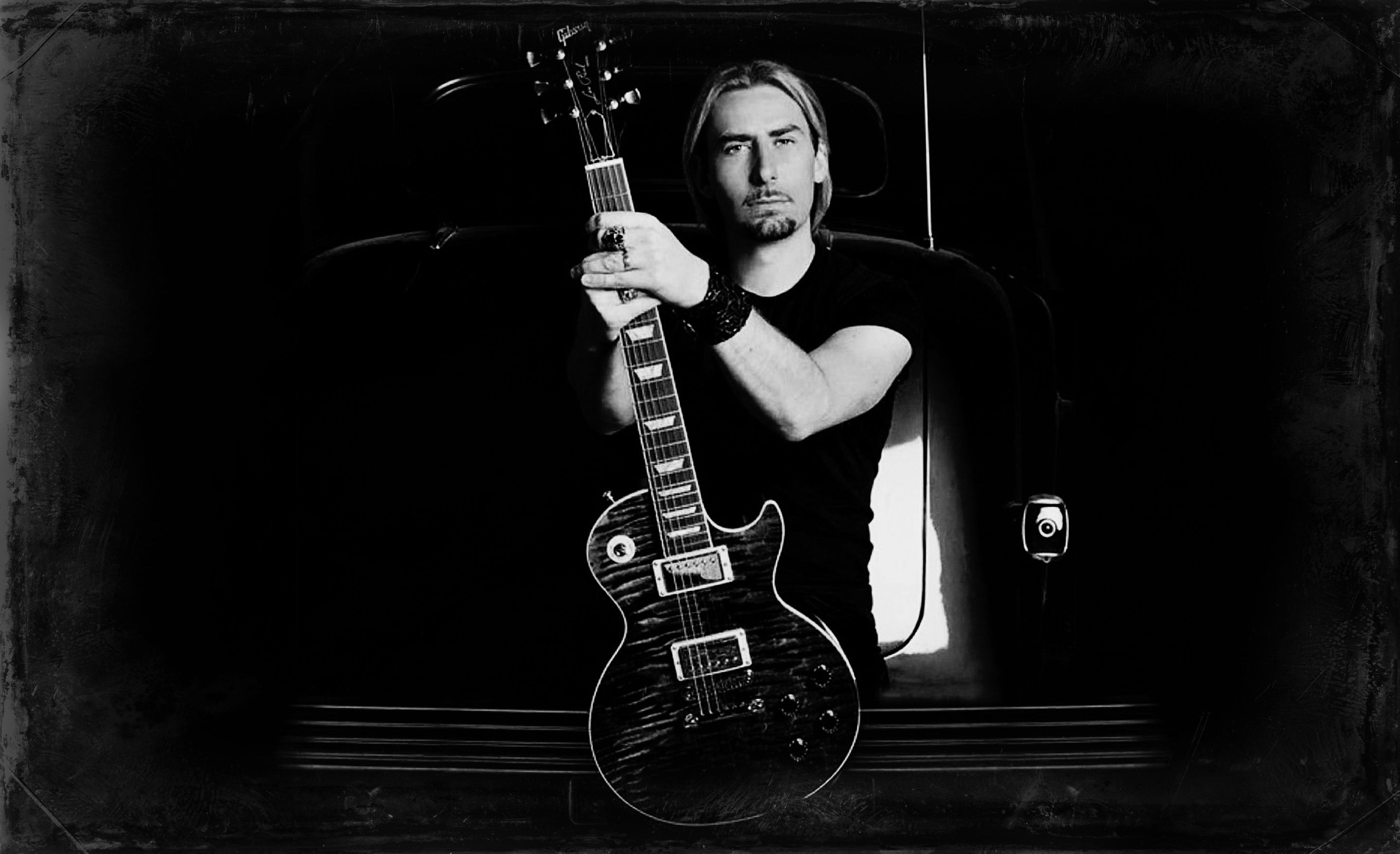 Chad Kroeger portrait in black and white by Mark Maryanovich sitting on back bumper of vintage car holding custom Blackwater Les Paul guitar upright in his lap