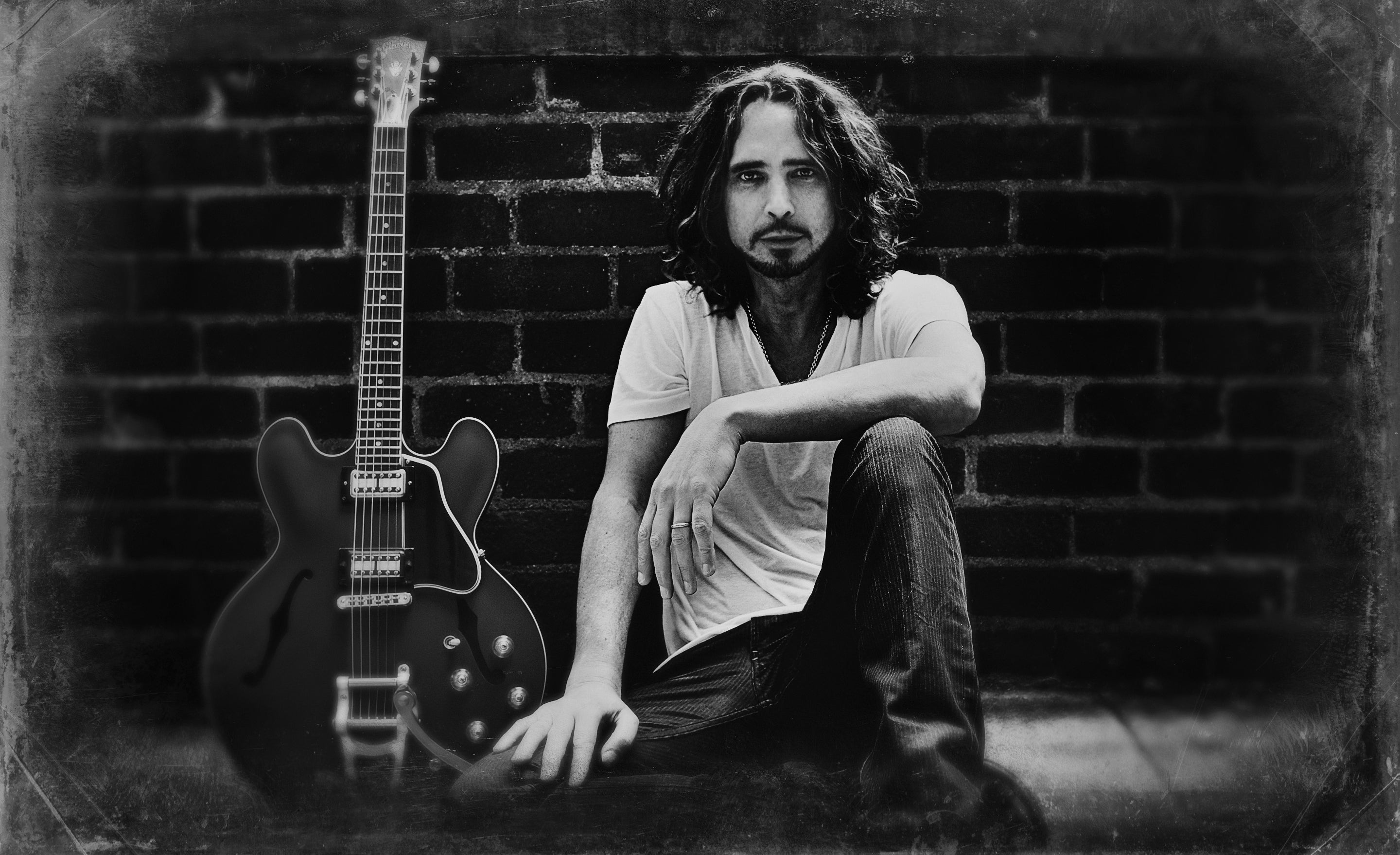 Chris Cornell portrait in black and white sitting against brick wall Gibson ES-335 leaning beside him by Mark Maryanovich