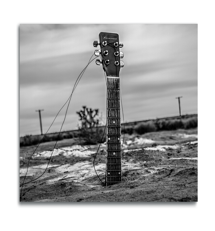 Fine Art black and white metal square print guitar neck protruding from body buried in desert sand