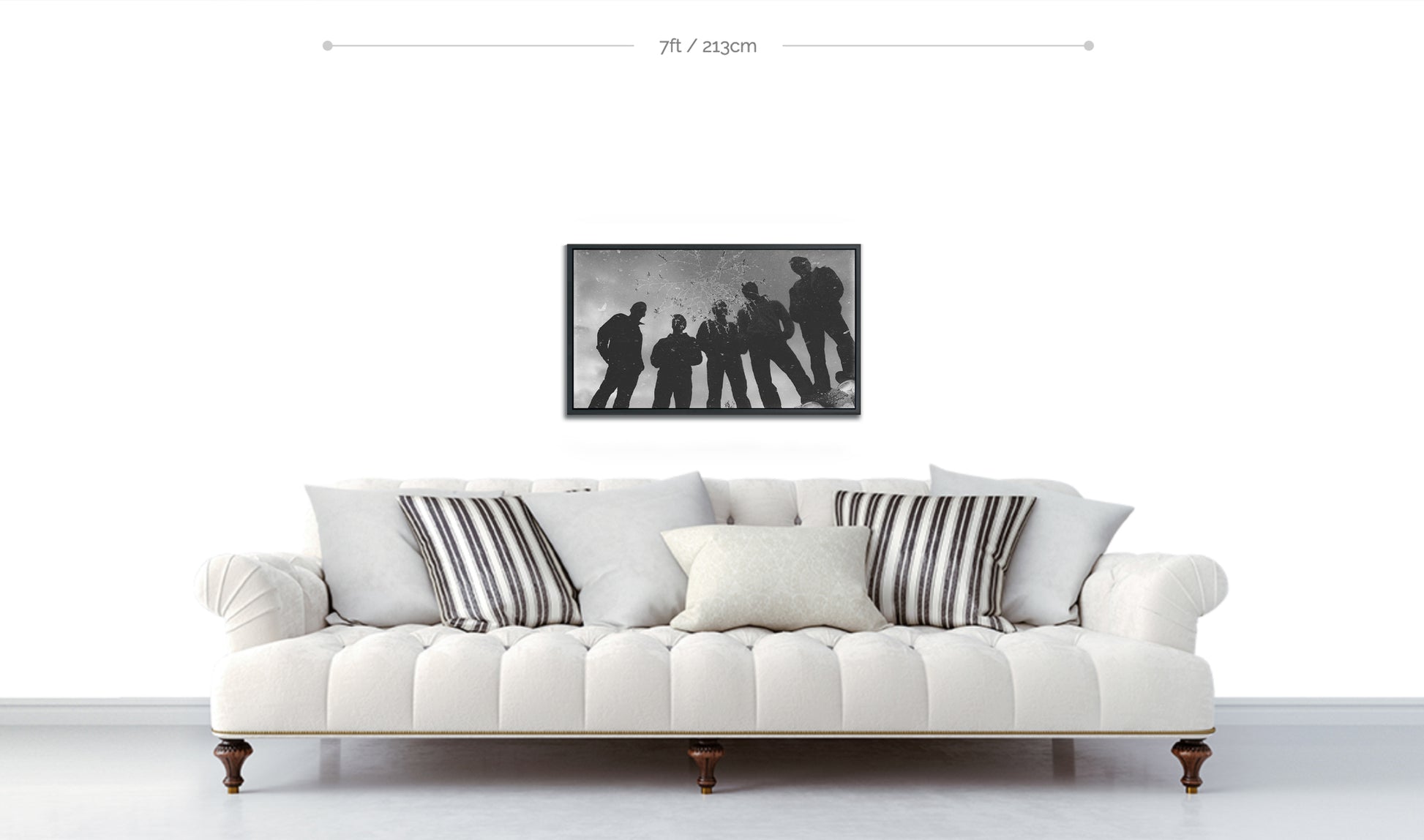 Framed black and white fine art print silhouettes of five guys in reflection of puddle with weed floating at top of frame displayed above white sofa on white wall