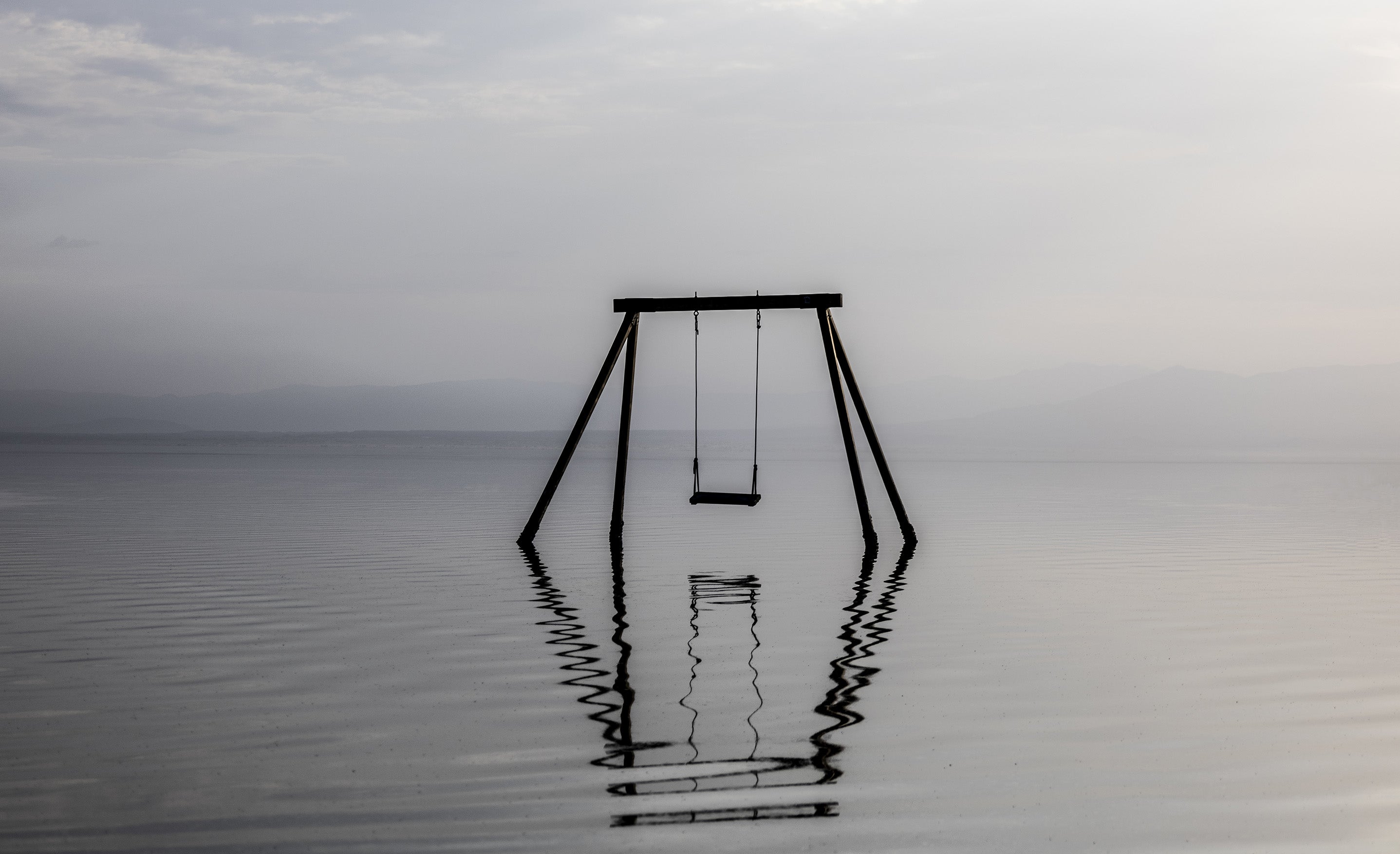 Solitary swing set immersed in water photographed in muted colors